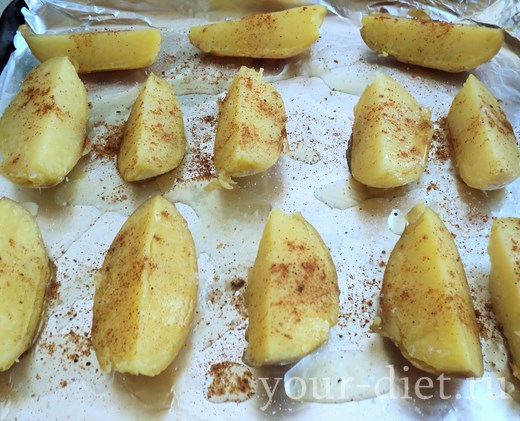 Дольки картофеля на фольге, посыпанные специями